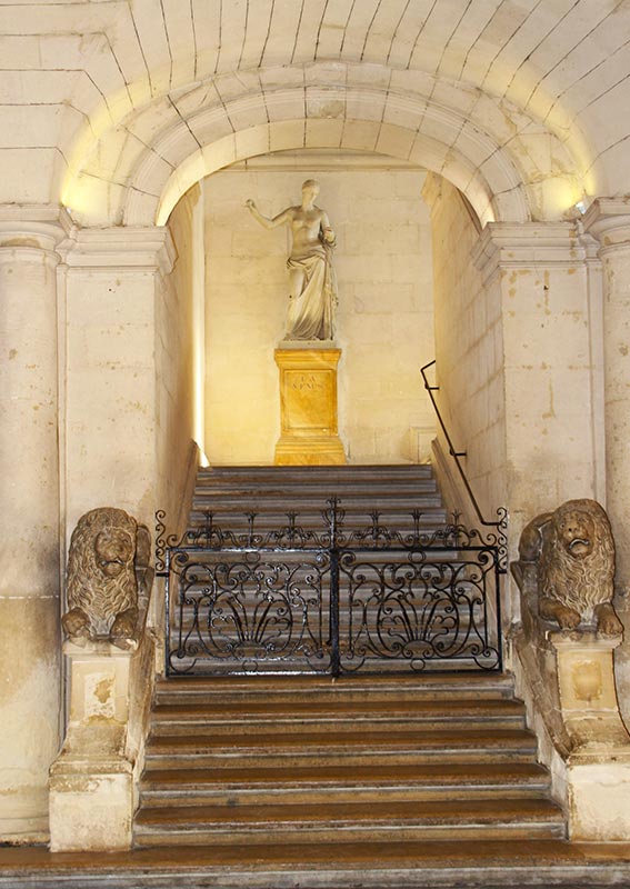 Vue sur sur des escaliers avec une statue en haut des marches.