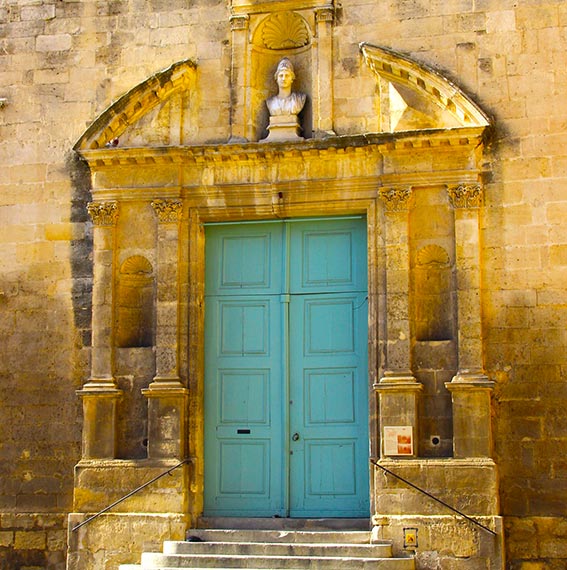 Vue sur une porte bleu d'un bâtiment ancien avec une statue au-dessus