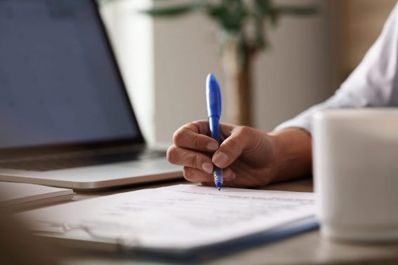 Gros plan d'une femme d'affaires signant des documents au bureau.